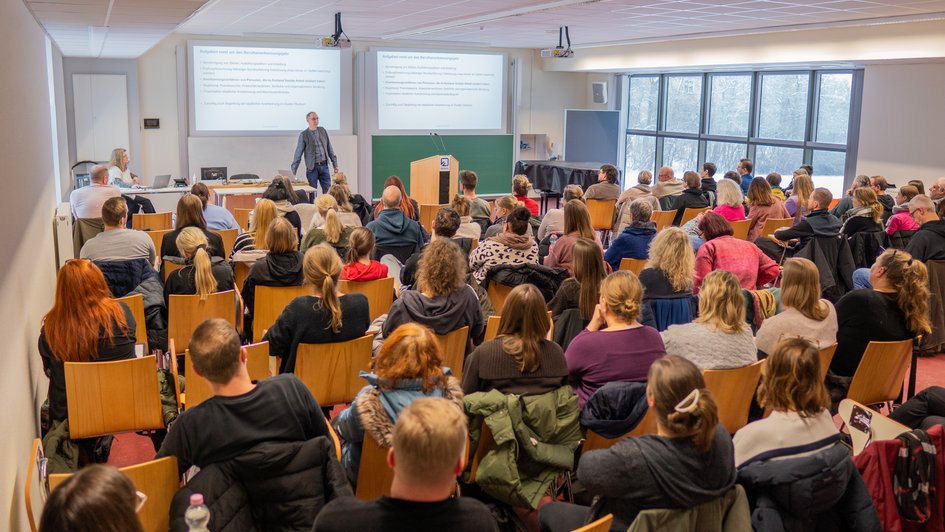 Karl-Heinz Gröpler steht vor über 70 Anleiter*innen und tritt mit ihnen in einen intensiven Dialog, um die Zusammenarbeit zu verbessern.