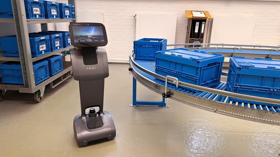 Fahrender Roboter neben einem Band mit Kisten