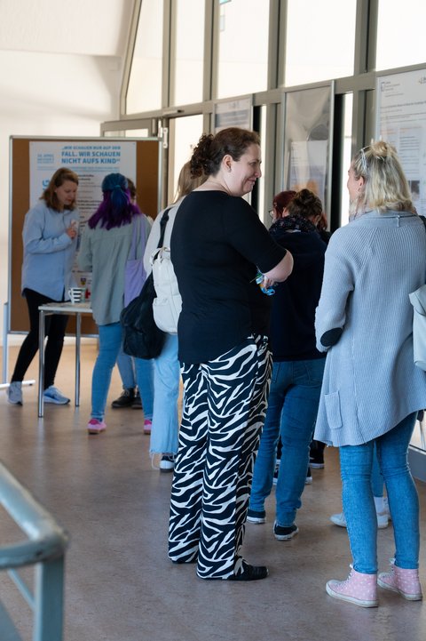 The visitors are standing in the foyer on the first floor and can be seen from behind, waiting to register for the conference. (opens enlarged image)