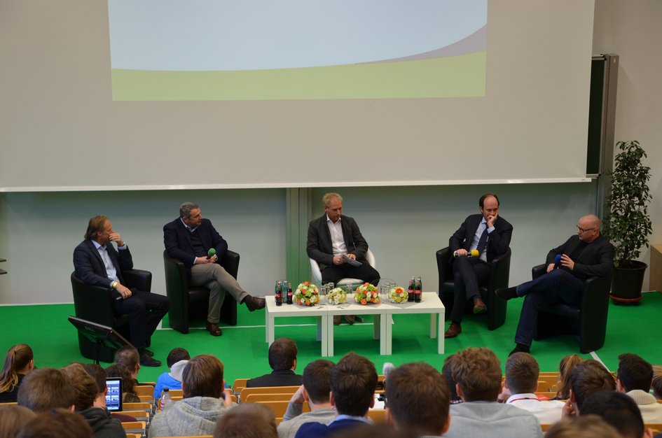 Vier Referenten sitzen mit dem Moderator auf der Bühne.
