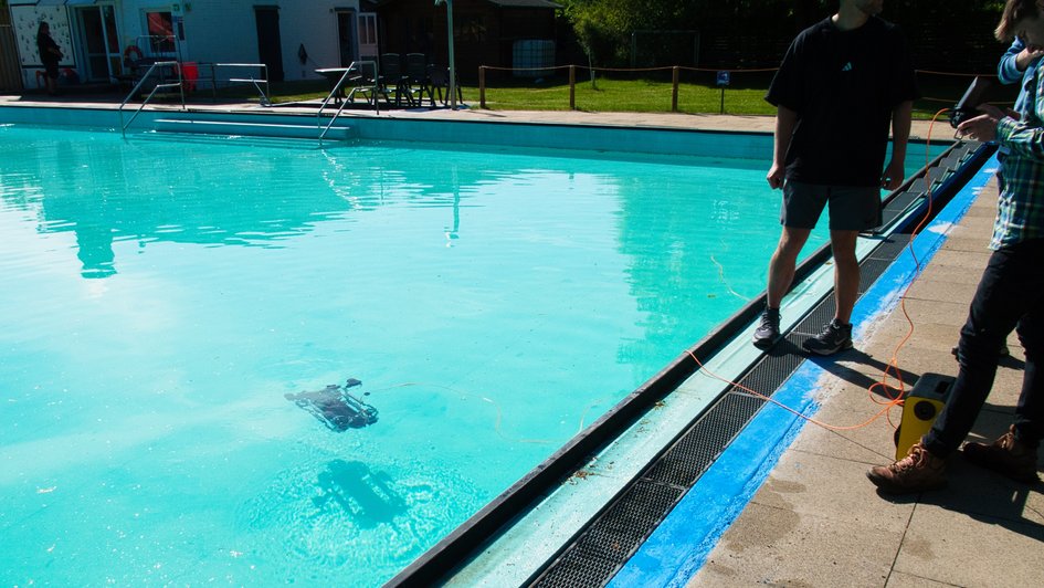 Masterstudierende üben die Stuerung einer Unterwasserdrohne in einem Schwimmbad.