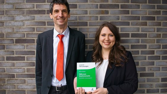 Prof. Dr. Udo Wolfgang Becker und Isabel Weibler halten ihr Lehrbuch "Fälle zum Insolvenzrecht" in den Händen.