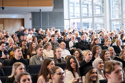 Blick von der Bühne Richtung Sitzreihen, in denen sich die Absolvent:innen und ihre Gäste befinden. (öffnet Vergrößerung des Bildes)