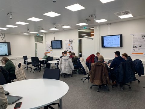 Lehrraum mit Studierenden, die in an Gruppentischen arbeiten
