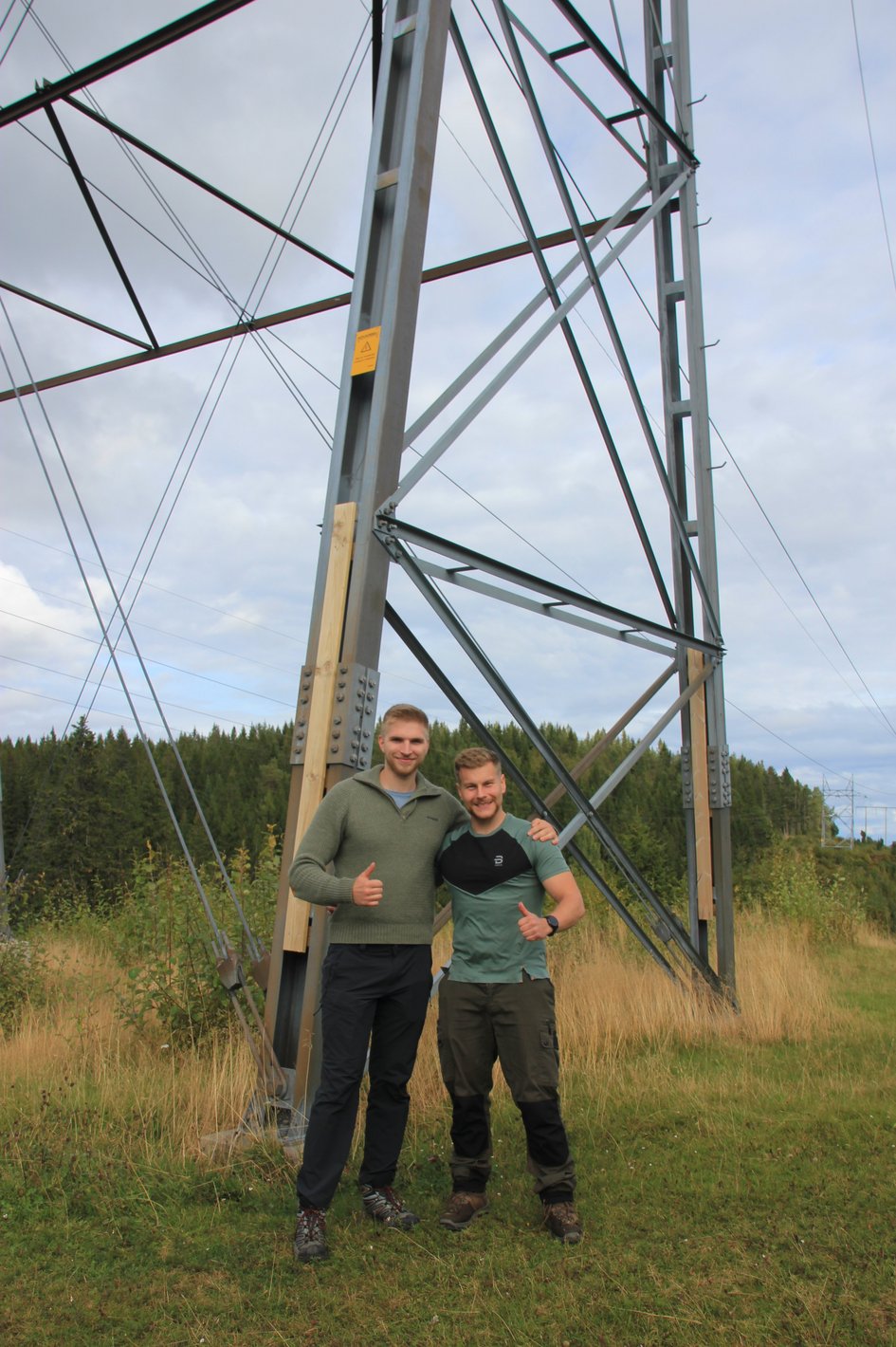 Die zwei Studierenden Luis und Adrian in Trondheim vor einem Strommast
