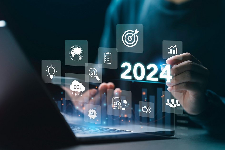 Dekorativ: Hände vor Laptop mit schwebenden Symbolen für Ziel, Wachstum, CO2, KI und 2024, symbolisieren strategische Unternehmensberatung