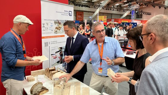 Die Ostfalia auf der IdeenExpo in Hannover: Prof. Dr. Ingo Johannsen (links) und Prof. Dr. Max Ehleben (rechts) erläutern Wissenschaftsminister Falko Mohrs (zweiter von links) die Forschung der Hochschule im Bereich zirkulärer Rohstoffe und Pilz-Myzel.