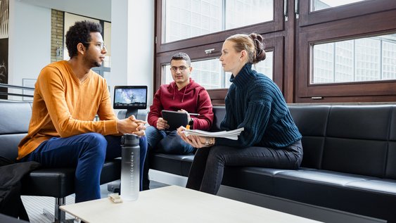 Drei Personen sitzen zusammen und unterhalten sich