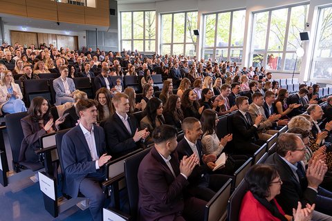 Die Personen im vollbesetzten Auditorium der Aula applaudieren während der Abschlussfeier. (öffnet Vergrößerung des Bildes)