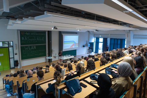 Die Dekanin der Fakultät Prof. Dr. Sandra Müller steht vorne im Hörsaal und begrüßt die Erstsemester. (öffnet Vergrößerung des Bildes)