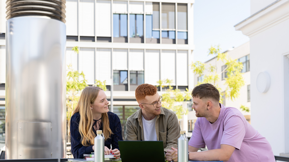 Studierende an Stehtisch vor der Mensa