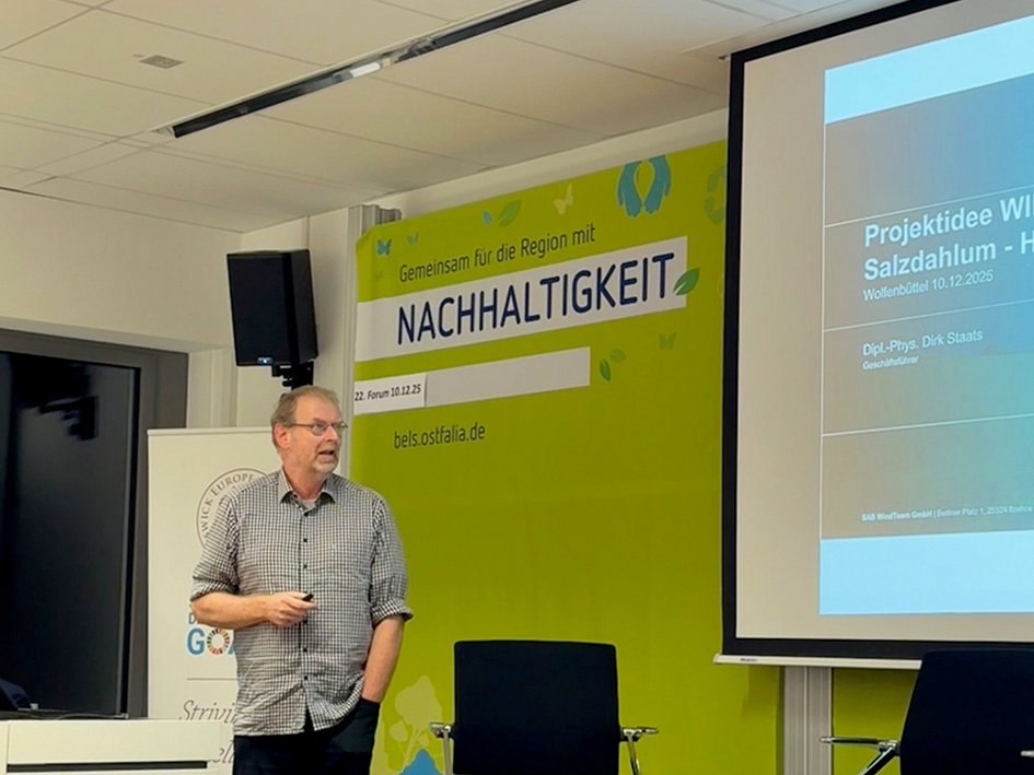 Dirk Staats steht am Rednerpult und hält seinen Vortrag beim Forum Nachhaltigkeit. Hinter ihm ist ein Teil seiner PowerPoint-Folie zu sehen.
