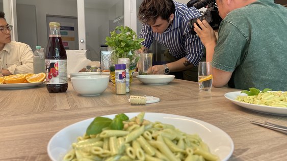 Pasta steht auf dem Tisch. Im Hintergrund sind Studierende.