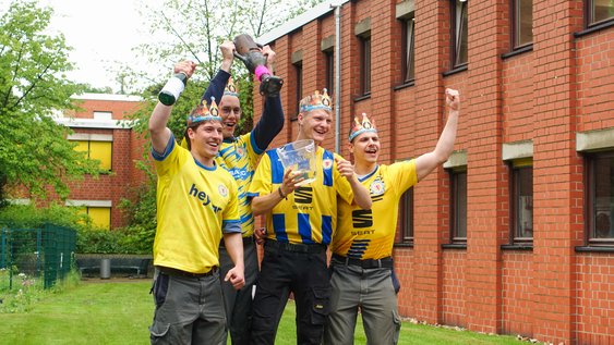 Gruppenbild der diesjährigen Gewinner vom Wettbewerb Gladiatrohr 2026. Vier Studierende jubeln und tragen Eintracht Braunschweig Trikots.