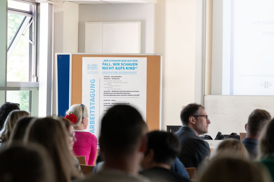 View from the audience's perspective of the conference programme, which is displayed on a pinboard at the front left of the hall.