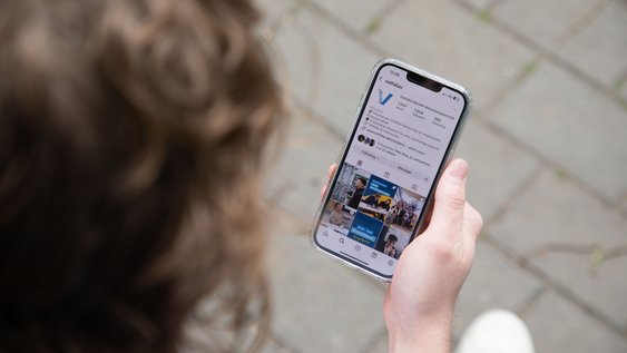 Studierender schaut sich auf dem Smartphone die Instagramseite der Fakultät Versorgungstechnik an. 