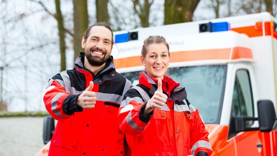 Sanitäter und Sanitäterin vor Rettungswagen