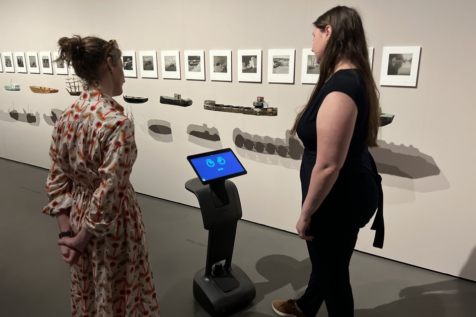 Museumsbot Carl spricht im Museum mit zwei Frauen