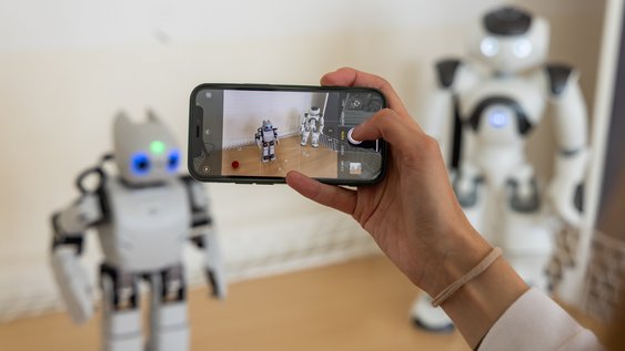 Roboter der Ostfalia Hochschule für angewandte Wissenschaften werden mit einem Smartphone gefilmt.