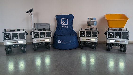 4 Roboter mit einem Sitzsack in der Mitte
