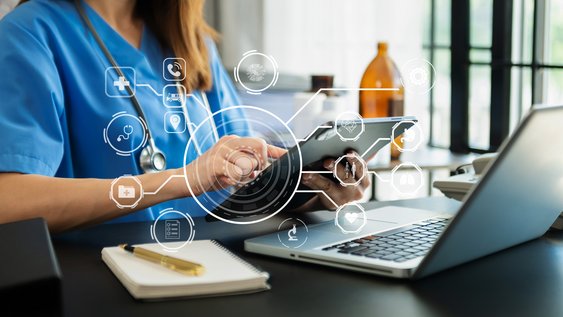 Pflegerin am Laptop mit Tablet am Arbeiten