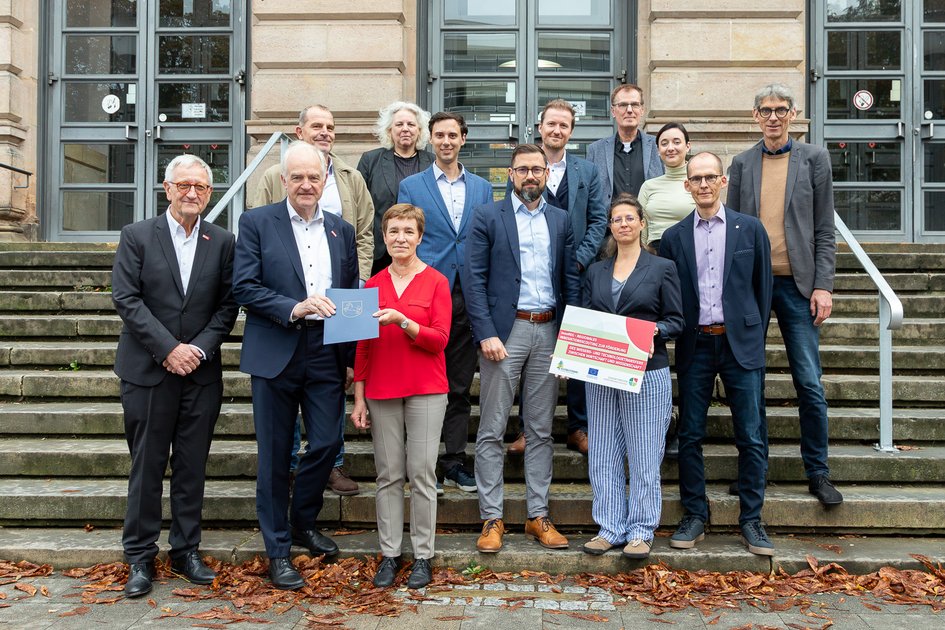 Übergabe des InnoREG-Förderbescheides am 8. Oktober 2025 (vom links nach rechts, erste Reihe zuerst): Jörg Saathoff (Leitung Technologietransfer TU Braunschweig; Prof. Arno Kwade, Vizepräsident für Transfer und Innovation, TU Braunschweig; Astrid Paus, Dezernatsleitung, Amt für regionale Landesentwicklung Braunschweig; Sebastian Hallmann, Referatsleiter, Stadt Braunschweig; Sandra Lindemann, Regionalverband Großraum Braunschweig- Zukunftsregion SON, Björn Hobus, Projektkoordination InnoREG, TU Braunschweig; Kai Hillebrecht, Leitung Wissens- und Technologietransfer, Ostfalia HaW, Nathalie Hauer, Unternehmensservice & Gründung, Wirtschafts- und Innovationsförderung Salzgitter GmbH; Mathis Vetter, Bereichsleiter Innovationsförderung, Braunschweig Zukunft GmbH; Andreas Wiegand, Geschäftsführung, Landkreis Gifhorn Innovation & Service GmbH; Hartmut Keune, Support Antragstellung EU-Projekte, TU Braunschweig, Julia Mehring, Projektkoordinatorin Transfer und Transformation, Ostfalia HaW; Andreas Hebbelmann, Leitung Stabstelle Forschungsservice, TU Braunschweig. 