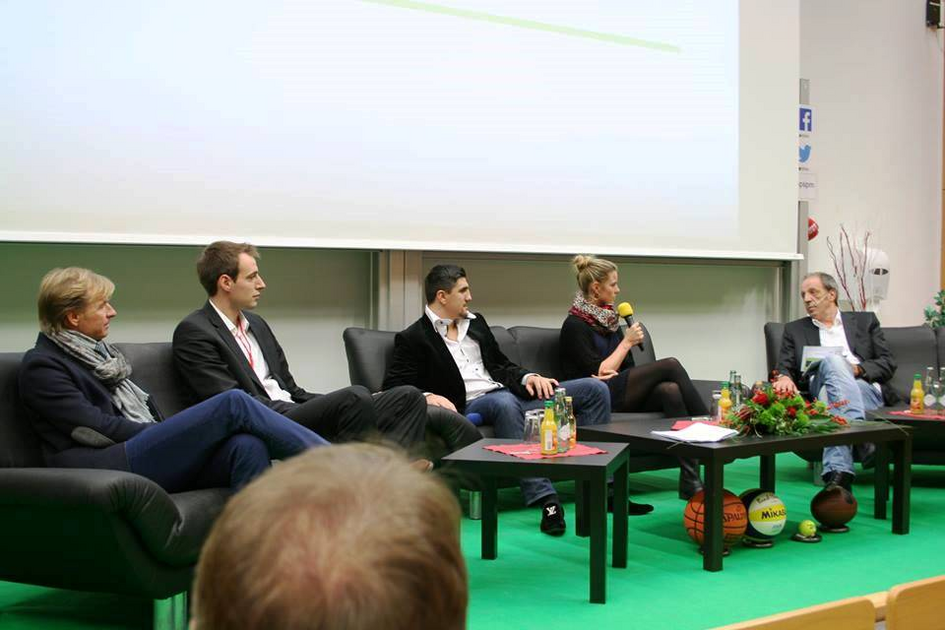 Moderator und Diskussionsteilnehmer sitzen gemeinsam auf der Bühne