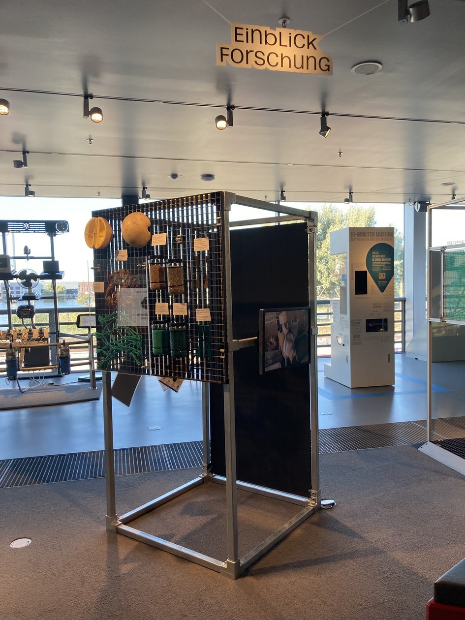 Ausstellungsstation „Einblick Forschung“ im phaeno mit Fischernetzmaterialien, Proben aus recyceltem Kunststoff und einem Bildschirm mit Einblicken in die Materialverarbeitung.