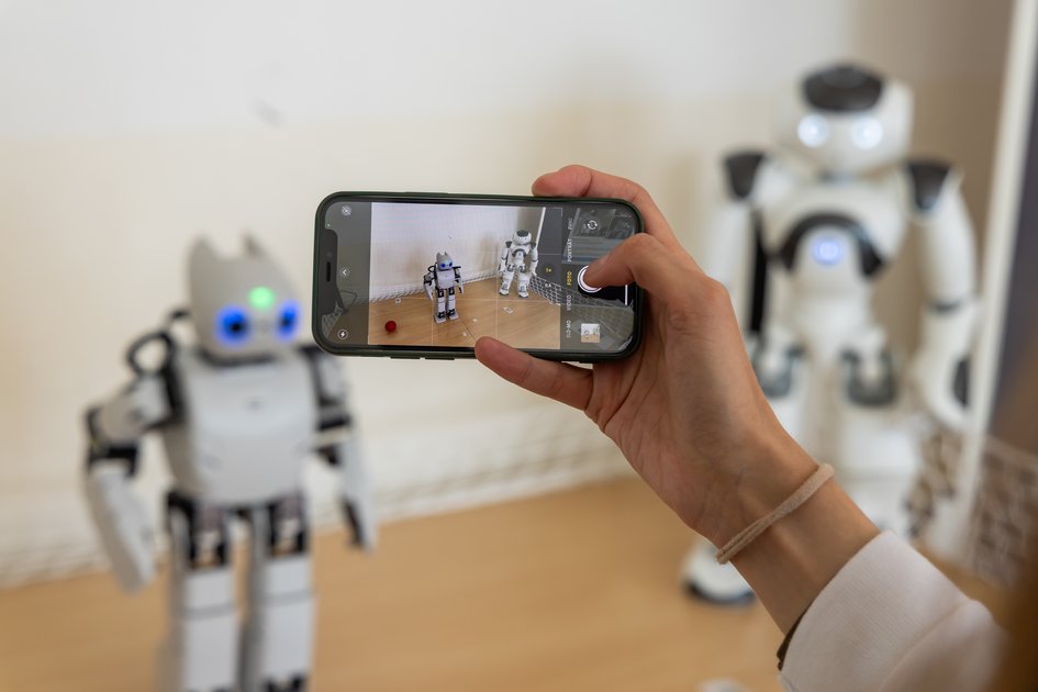 Roboter Robbi wird mit einem Handy fotografiert
