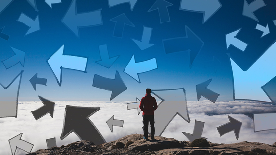 Ein Mann steht auf einem Gipfel und um ihn herum sind viele Pfeile in verschiedene Richtungen