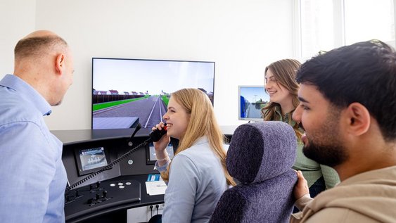 Studierende lernen mit ihrem Professor am Bahnsimulator für die Praxis.