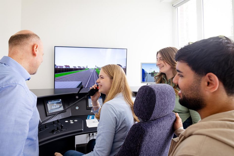 Studierende lernen mit ihrem Professor am Bahnsimulator für die Praxis.