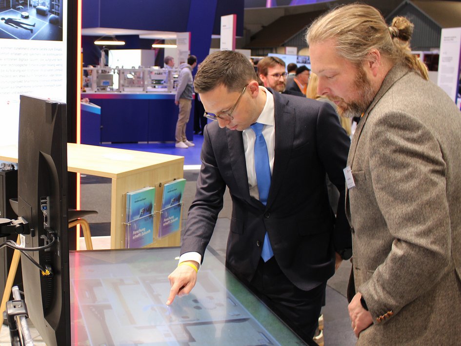 Minister Falko Mohrs in conversation with Prof Dr Felix Büsching from Ostfalia University of Applied Sciences and Arts at Hannover Messe 2026.