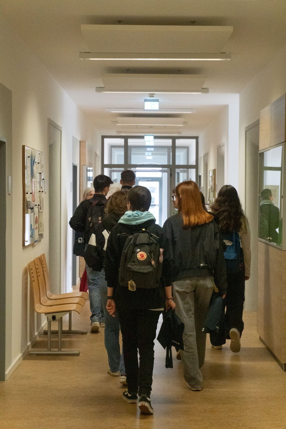 Die Schüler:innen sind von hinten zu sehen, während sie durch einen Flur laufen. Sie machen einen Rundgang durch die ganze Fakultät.