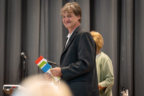 Prof. Dr. Jürgen Boeckh steht auf der Bühne und hält eine Urkunde in der Hand. (öffnet Vergrößerung des Bildes)