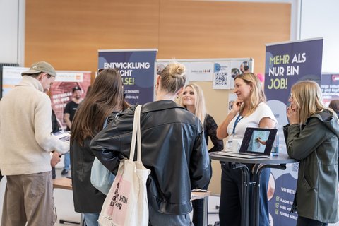 Studierende an einem Stand im Dialog mit Vertreterinnen des Trägers (öffnet Vergrößerung des Bildes)