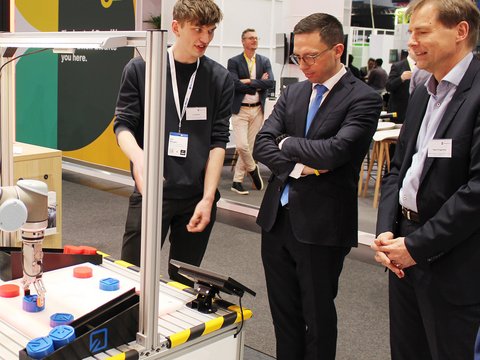 Minister Falko Mohrs in conversation with researchers from Ostfalia University of Applied Sciences and Arts at Hannover Messe 2026. (opens enlarged image)