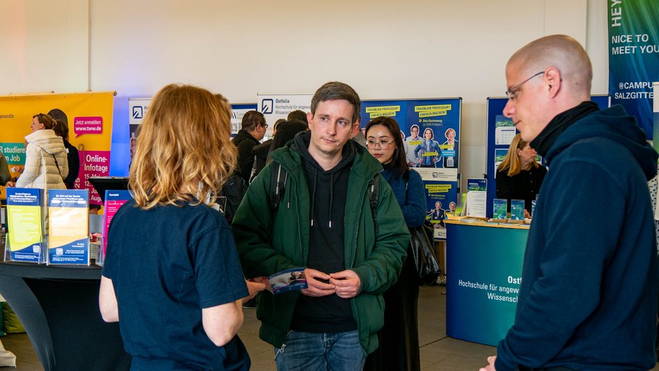 Info-Stand mit Ostfalia-Mitarbeitenden und Interessiertem