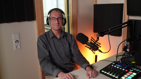 Christoph Rohmann sitzt im Podcast-Studio der Ostfalia Hochschule vor einem Mikrofon. In der Folge des Podcasts „Einfach Forschung“ spricht er mit Prof. Dr. Heinz-Dieter Quack über automatisiertes Fahren und die Mobilität der Zukunft.