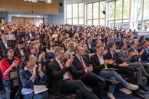 Die Personen im vollbesetzten Auditorium der Aula applaudieren während der Abschlussfeier. (öffnet Vergrößerung des Bildes)