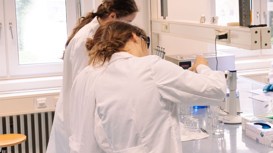 Schülerinnen im Chemielabor mit Laborkittel und Schutzbrille.