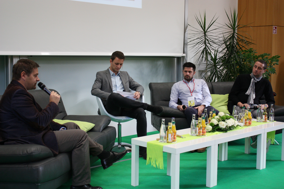 Moderator und drei Gäste sitzen in einer Diskussionsrunde auf der Bühne