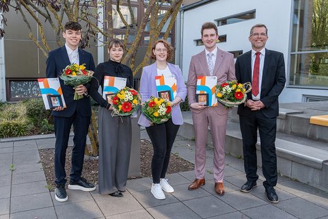 Gruppenbild mit den vier Preisträgerinnen und Preisträgern sowie dem Dekan. Die Abgebildeten lächeln in die Kamera. Die Ausgezeichneten halten ihre Awards und Blumensträuße. (öffnet Vergrößerung des Bildes)