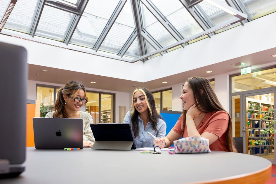 Drei Studierende sitzen zusammen und haben Laptops vor sich