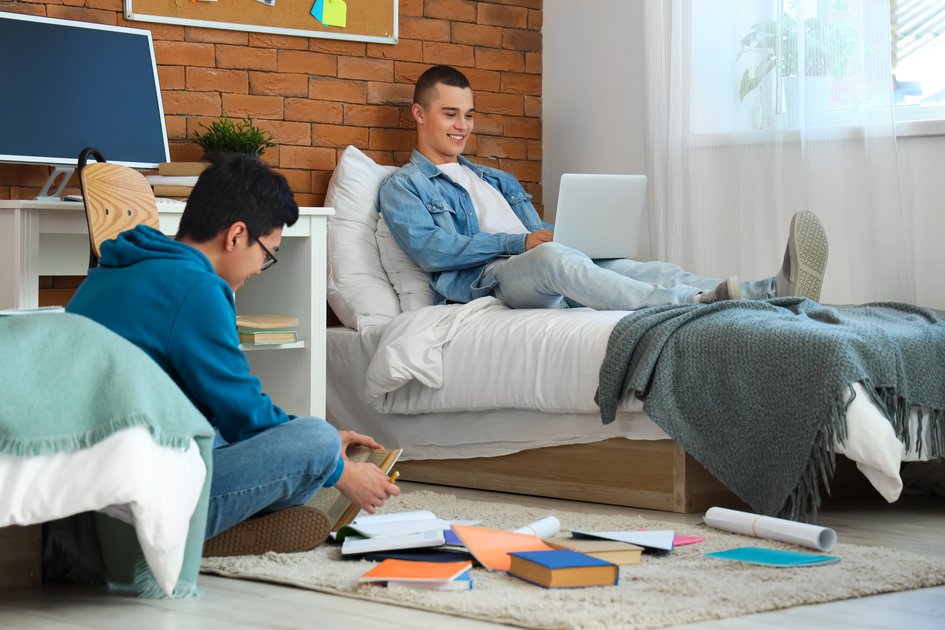 Zwei Studenten sitzen im WG-Zimmer und lernen zusammen