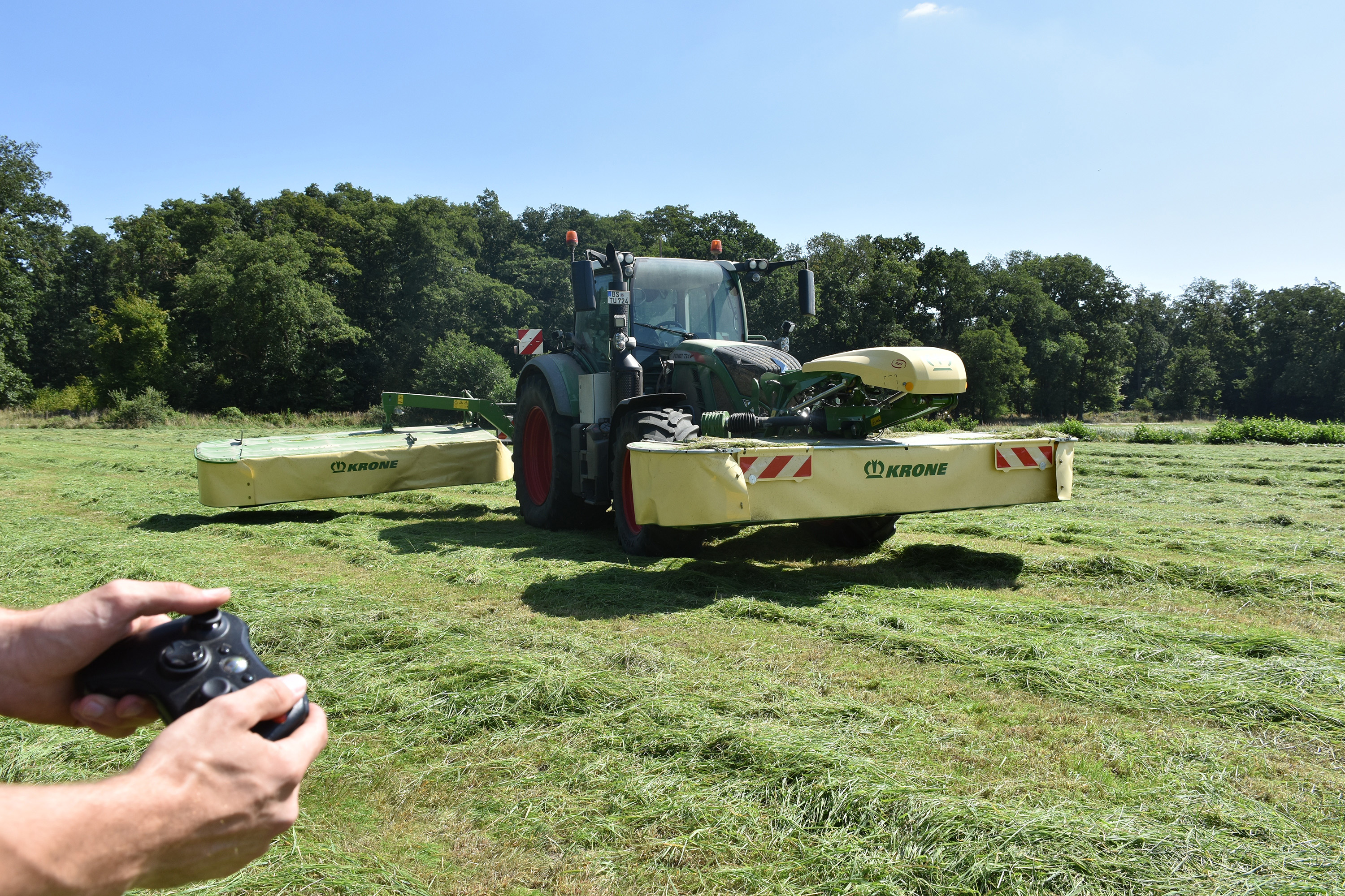Pressefoto (Adrian Grimm): Das Symbolbild zeigt einen Traktor mit Front- und Heckmähwerk sowie einen Controller. An verschiedenen Möglichkeiten und Rahmenbedingungen der externen Steuerung als Schritt zur Automatisierung landwirtschaftlicher Maschinen und Prozesse wird im Projekt GESAL gearbeitet.