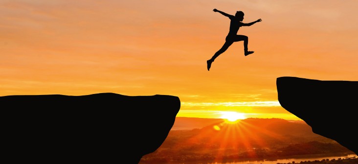 Man jumping on a mountain at sunset. The pose symbolises freedom.