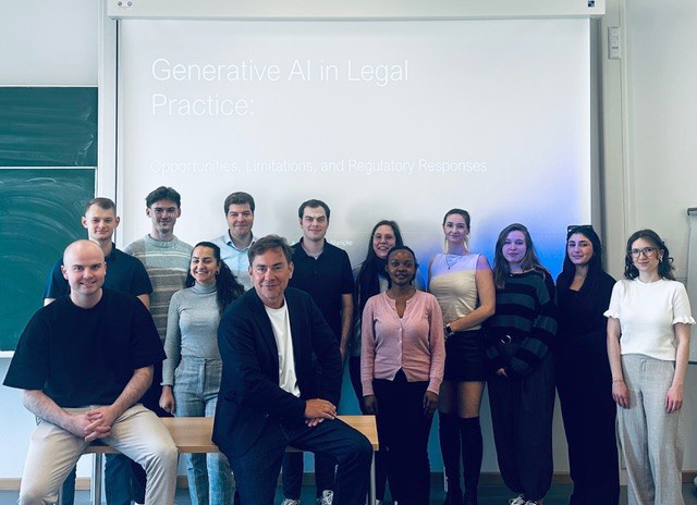 Gruppenbild der Teilnehmerinnen und Teilnehmer des LegalTech-Blockseminars zusammen mit Prof. Dr. Stancke (2. v l. in Reihe 1), auf der Beamerfläche hinter den Personen ist eine Präsentation mit dem Thema "Generative AI in Legal Practice" zu sehen.